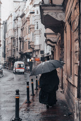 Vrouw loopt met paraplu door oude stadsstraat