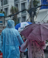 Mensen lopen in de regen met paraplu's en poncho's